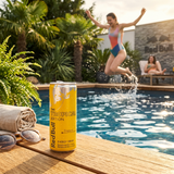 Cannette Red Bull Yellow Tropical au bord d’une piscine avec ambiance estivale et une personne sautant dans l’eau.